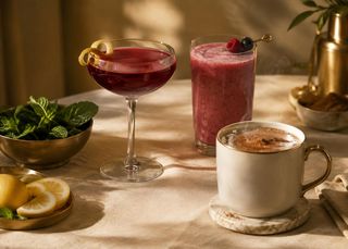 A burgundy cocktail, a berry smoothie and a mug of hot chocolate on an ivory tablecloth